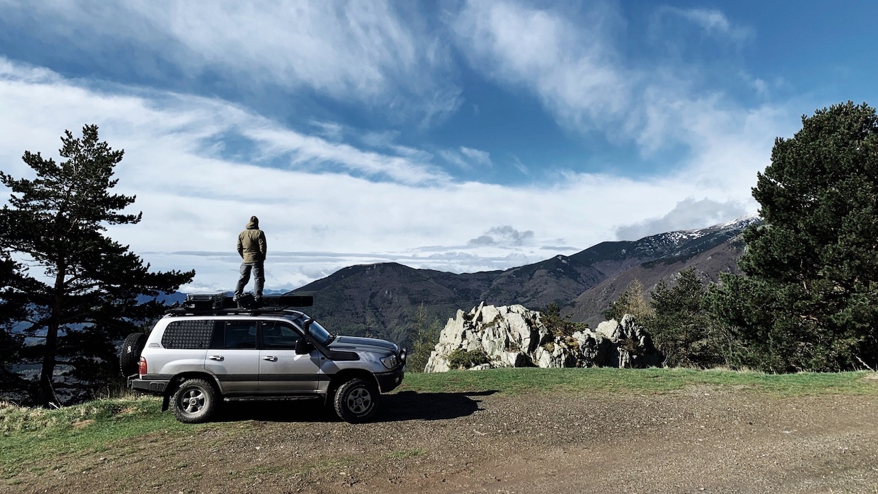Me standing on the Roof Rack of the Land Cruiser 100 on a mountain road.